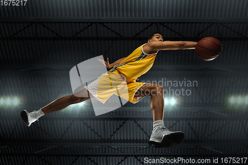 Image of Young professional basketball player in action, motion isolated on black background, look from the bottom. Concept of sport, movement, energy and dynamic.