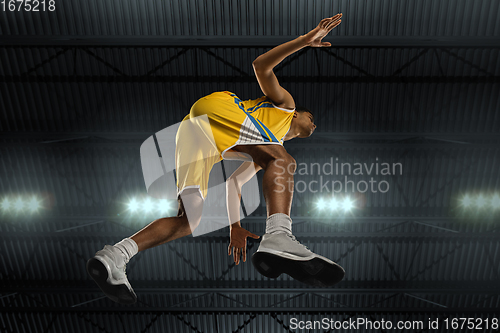 Image of Young professional basketball player in action, motion isolated on black background, look from the bottom. Concept of sport, movement, energy and dynamic.