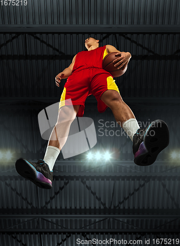 Image of Young professional basketball player in action, motion isolated on black background, look from the bottom. Concept of sport, movement, energy and dynamic.