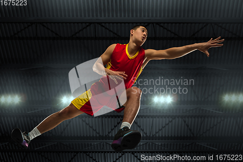 Image of Young professional basketball player in action, motion isolated on black background, look from the bottom. Concept of sport, movement, energy and dynamic.