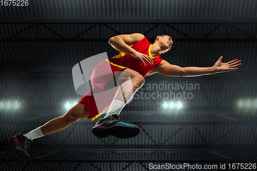 Image of Young professional basketball player in action, motion isolated on black background, look from the bottom. Concept of sport, movement, energy and dynamic.