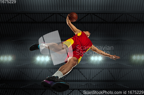 Image of Young professional basketball player in action, motion isolated on black background, look from the bottom. Concept of sport, movement, energy and dynamic.