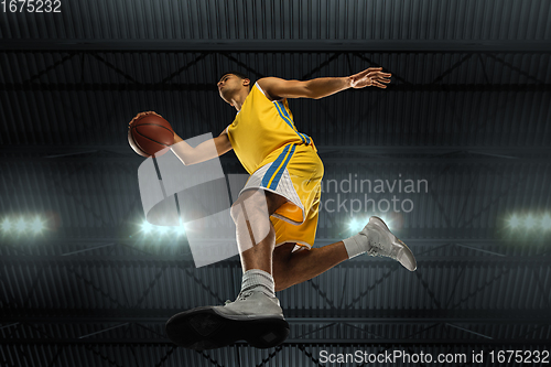 Image of Young professional basketball player in action, motion isolated on black background, look from the bottom. Concept of sport, movement, energy and dynamic.