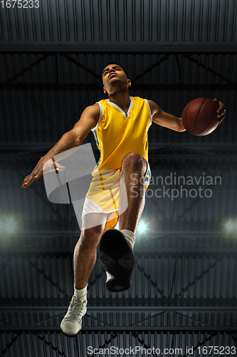 Image of Young professional basketball player in action, motion isolated on black background, look from the bottom. Concept of sport, movement, energy and dynamic.