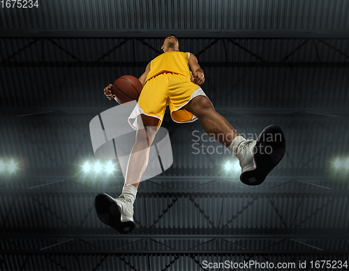 Image of Young professional basketball player in action, motion isolated on black background, look from the bottom. Concept of sport, movement, energy and dynamic.