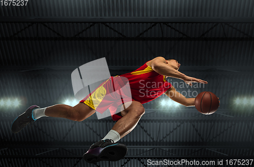 Image of Young professional basketball player in action, motion isolated on black background, look from the bottom. Concept of sport, movement, energy and dynamic.