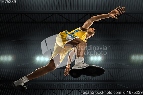 Image of Young professional basketball player in action, motion isolated on black background, look from the bottom. Concept of sport, movement, energy and dynamic.