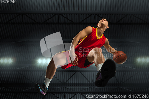 Image of Young professional basketball player in action, motion isolated on black background, look from the bottom. Concept of sport, movement, energy and dynamic.