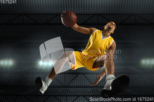 Image of Young professional basketball player in action, motion isolated on black background, look from the bottom. Concept of sport, movement, energy and dynamic.