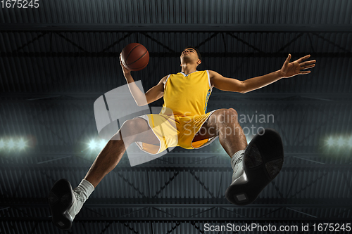 Image of Young professional basketball player in action, motion isolated on black background, look from the bottom. Concept of sport, movement, energy and dynamic.