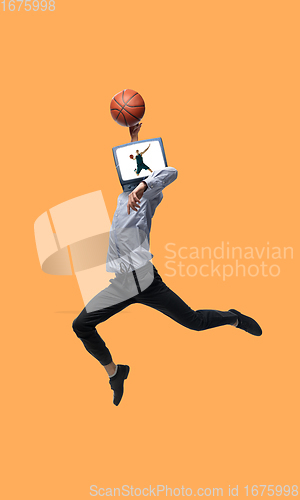 Image of Young man headed of TV set jumping as basketball player on orange background.