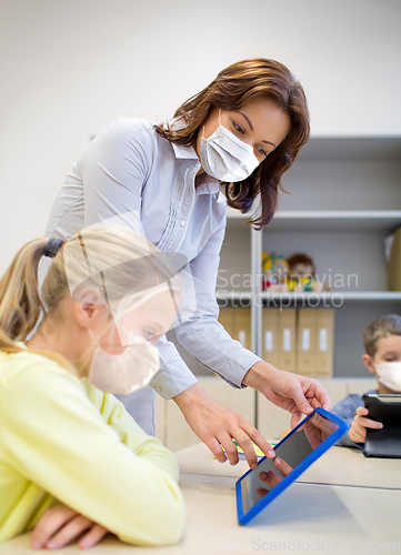 Image of school teacher and student in masks with tablet pc