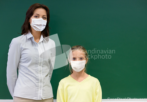 Image of student girl and teacher in masks at school