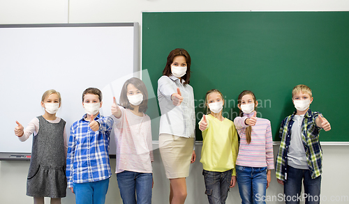 Image of students and school teacher in mask show thumbs up