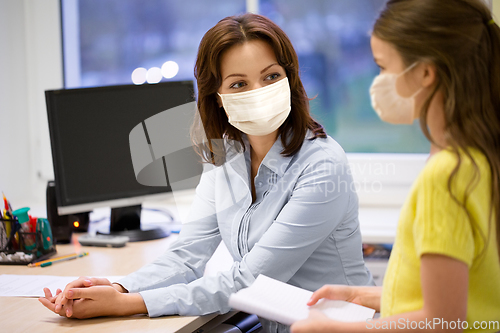 Image of teacher and student girl in masks at school