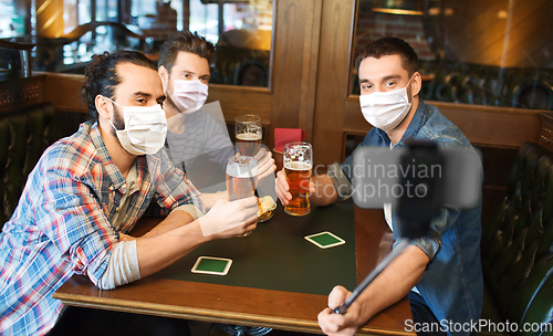 Image of men in masks take selfie and drink beer at bar