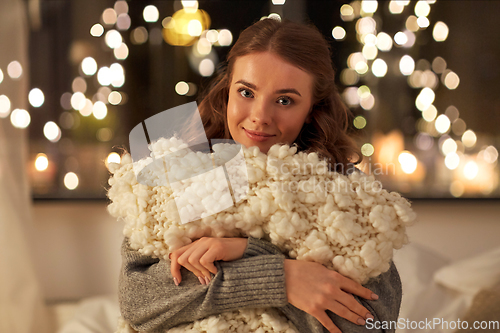 Image of happy young woman with soft pillow in bed at home