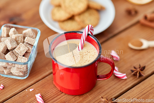 Image of cup of eggnog with candy cane, cookies and sugar