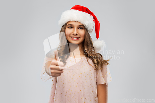 Image of happy teenage girl in santa hat showing thumbs up