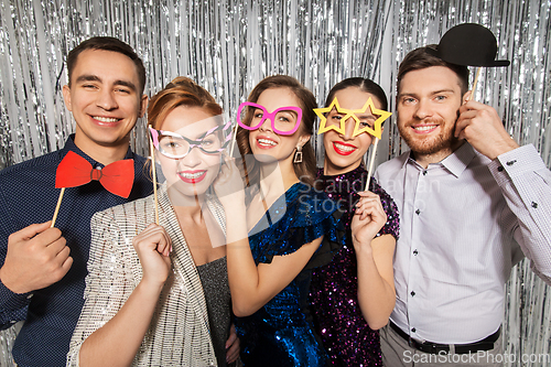 Image of happy friends posing with party props