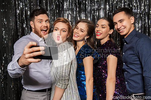 Image of happy friends taking selfie by smartphone at party