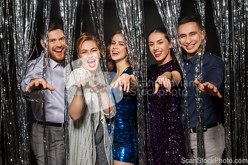 Image of happy friends in party clothes with tinsel curtain