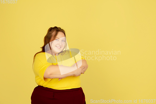 Image of Beautiful caucasian plus size model isolated on yellow studio background. Concept of inclusion, human emotions, facial expression