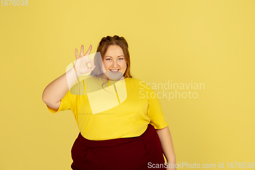 Image of Beautiful caucasian plus size model isolated on yellow studio background. Concept of inclusion, human emotions, facial expression