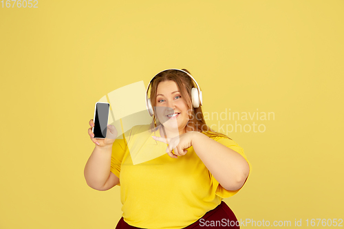 Image of Beautiful caucasian plus size model isolated on yellow studio background. Concept of inclusion, human emotions, facial expression