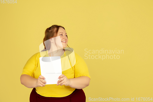 Image of Beautiful caucasian plus size model isolated on yellow studio background. Concept of inclusion, human emotions, facial expression