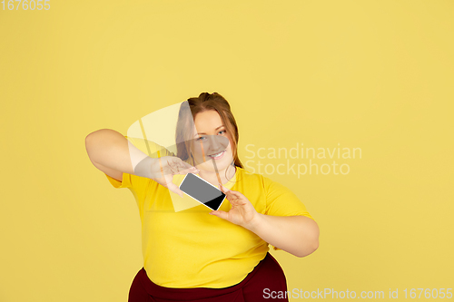 Image of Beautiful caucasian plus size model isolated on yellow studio background. Concept of inclusion, human emotions, facial expression