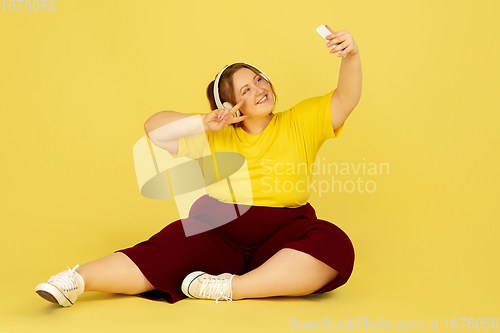 Image of Beautiful caucasian plus size model isolated on yellow studio background. Concept of inclusion, human emotions, facial expression