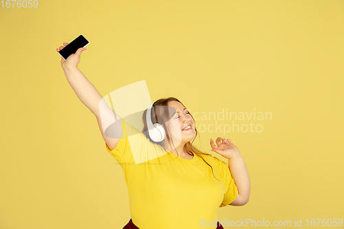 Image of Beautiful caucasian plus size model isolated on yellow studio background. Concept of inclusion, human emotions, facial expression