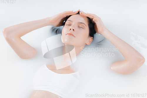 Image of Close up female face in the milk bath with soft white glowing. Copyspace for advertising. Beauty, fashion, style, bodycare concept.