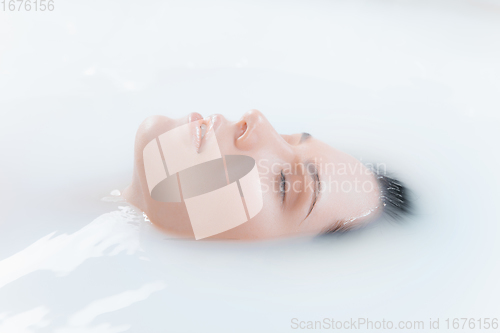 Image of Close up female face in the milk bath with soft white glowing. Copyspace for advertising. Beauty, fashion, style, bodycare concept.
