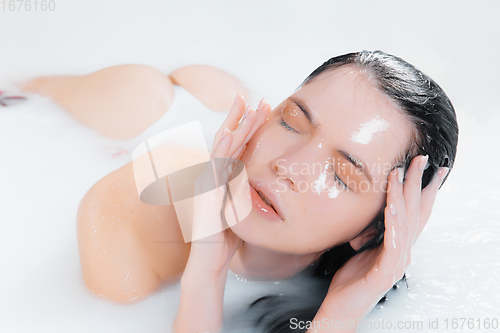 Image of Close up female model in the milk bath with soft white glowing. Copyspace for advertising. Beauty, fashion, style, bodycare concept.