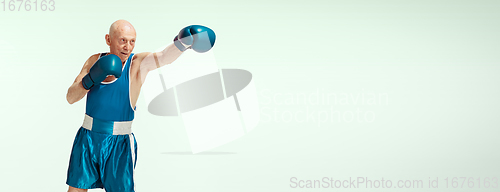 Image of Senior man wearing sportwear boxing isolated on studio background. Concept of sport, activity, movement, wellbeing. Copyspace, ad.