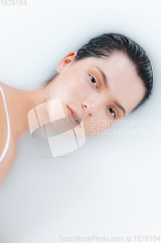 Image of Close up female face in the milk bath with soft white glowing. Copyspace for advertising. Beauty, fashion, style, bodycare concept.