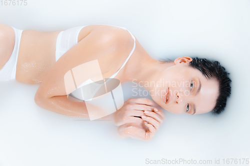 Image of Close up female model in the milk bath with soft white glowing. Copyspace for advertising. Beauty, fashion, style, bodycare concept.