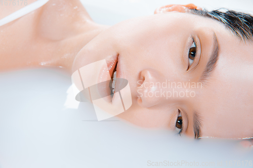 Image of Close up female face in the milk bath with soft white glowing. Copyspace for advertising. Beauty, fashion, style, bodycare concept.