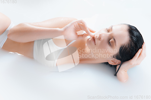 Image of Close up female model in the milk bath with soft white glowing. Copyspace for advertising. Beauty, fashion, style, bodycare concept.