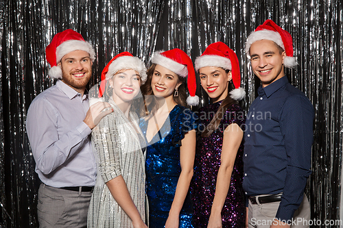 Image of happy friends in santa hats at christmas party