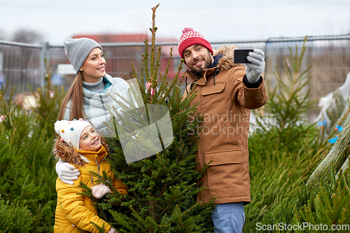 Image of family taking selfie with christmas tree at market