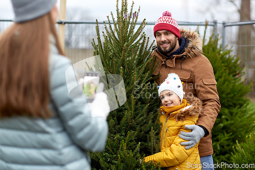 Image of family taking picture of christmas tree at market