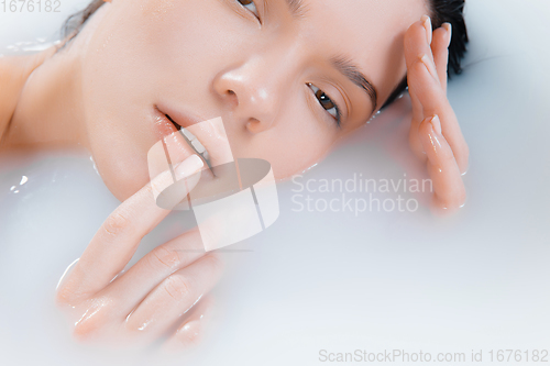 Image of Close up female face in the milk bath with soft white glowing. Copyspace for advertising. Beauty, fashion, style, bodycare concept.