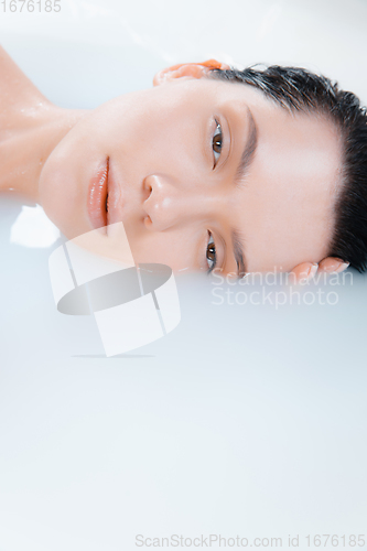 Image of Close up female model in the milk bath with soft white glowing. Copyspace for advertising. Beauty, fashion, style, bodycare concept.