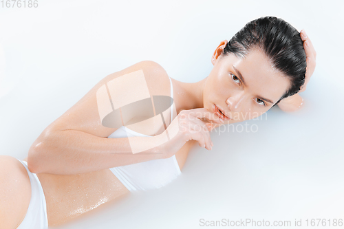 Image of Close up female model in the milk bath with soft white glowing. Copyspace for advertising. Beauty, fashion, style, bodycare concept.