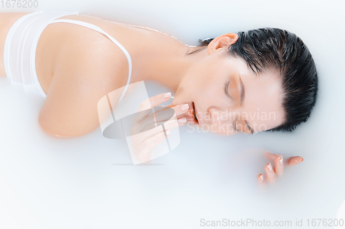 Image of Close up female model in the milk bath with soft white glowing. Copyspace for advertising. Beauty, fashion, style, bodycare concept.