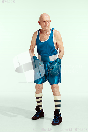 Image of Senior man wearing sportwear boxing isolated on studio background. Concept of sport, activity, movement, wellbeing. Copyspace, ad.