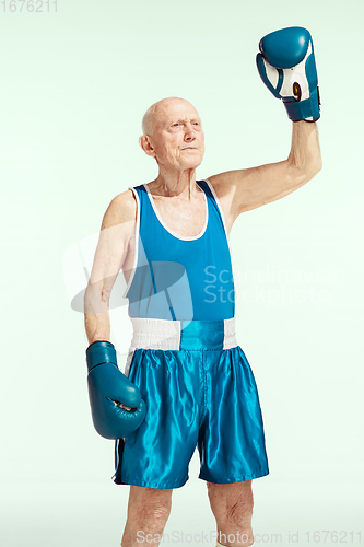 Image of Senior man wearing sportwear boxing isolated on studio background. Concept of sport, activity, movement, wellbeing. Copyspace, ad.